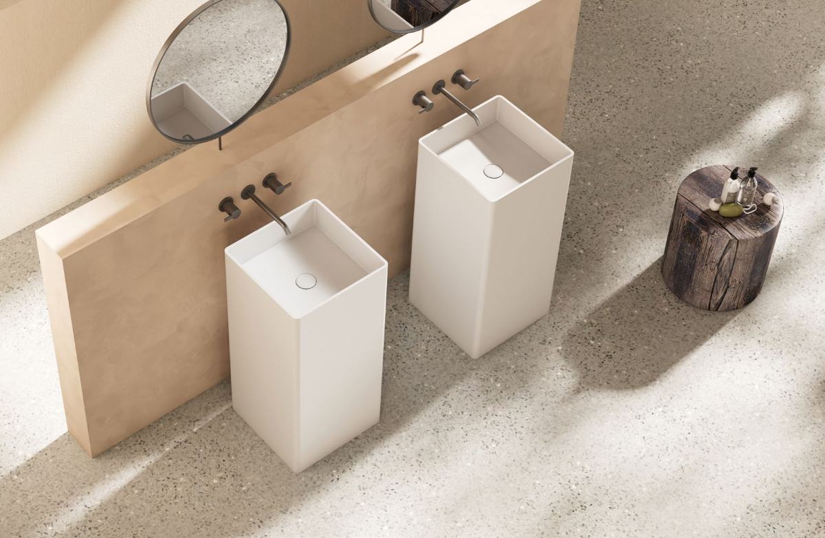Two square solid surface pedestal basins against a warm plaster wall